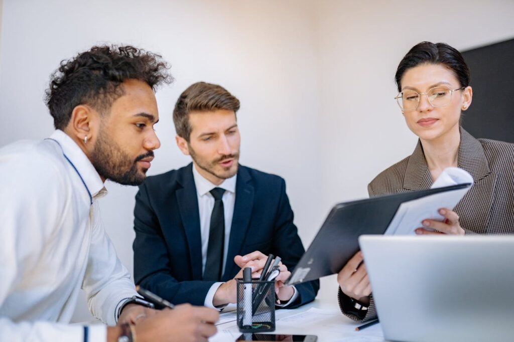 Three business professionals engaged in a focused office meeting, discussing documents.